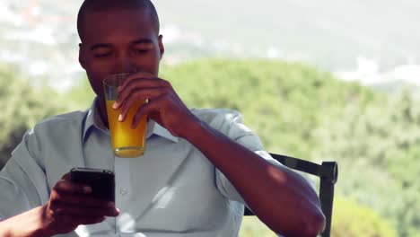 Man-using-mobile-phone-while-drinking-juice