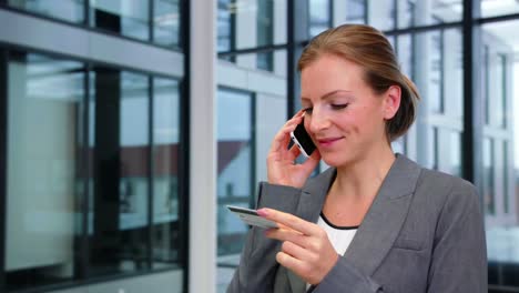 Businesswoman-using-credit-card-while-talking-on-mobile-phone