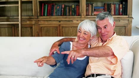Senior-couple-sitting-together-on-sofa-and-watching-tv