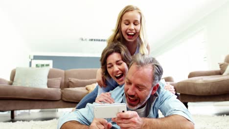 Glückliche-Familie,-Die-Auf-Dem-Teppich-Liegt-Und-Ein-Selfie-Mit-Dem-Handy-Macht