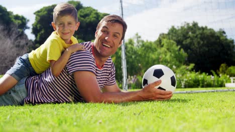 Porträt-Eines-Glücklichen-Vaters-Und-Sohnes-Mit-Fußball,-Der-Im-Park-Liegt