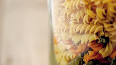 Close-up-of-colored-and-original-Fusilli-pasta-in-transparent-jar-glass