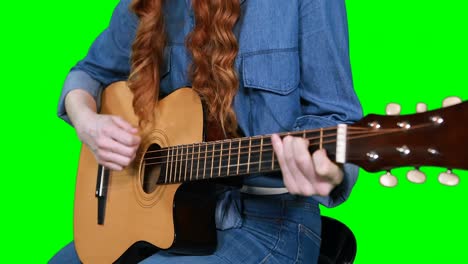 Mid-section-of-female-musician-playing-guitar