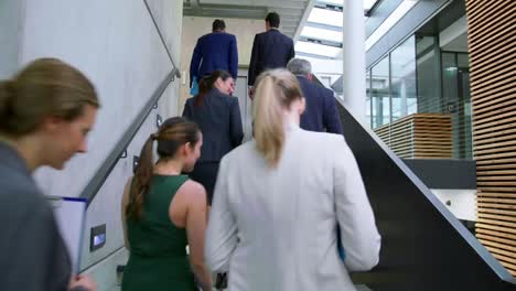 Businesspeople-interacting-with-each-other-while-walking-on-stairs