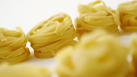 Close-up-of--parallel-roll-of-tagliatelle-pasta-on-white-background