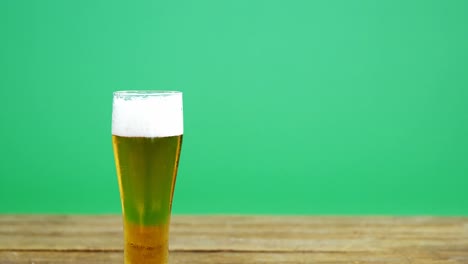 Pint-of-beer-on-wooden-table-with-green-background-for-st-patricks