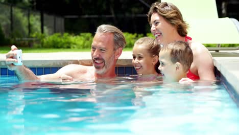 Family-taking-a-selfie-on-mobile-phone-in-swimming-pool