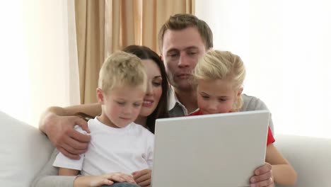 Familia-Joven-Usando-Una-Computadora-Portátil-En-Casa