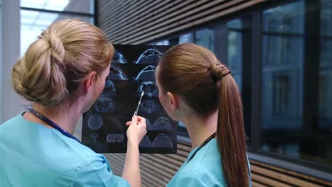 Two-nurses-examining-an-x-ray-report-in-corridor