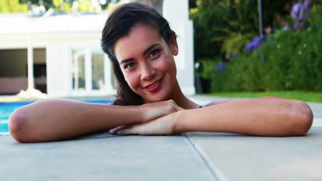 Woman-smiling-while-leaning-over-the-swimming-pool