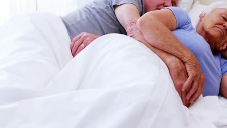 Senior-couple-sleeping-on-bed-in-bedroom