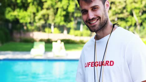 Smiling-lifeguard-writing-on-clipboard-at-poolside
