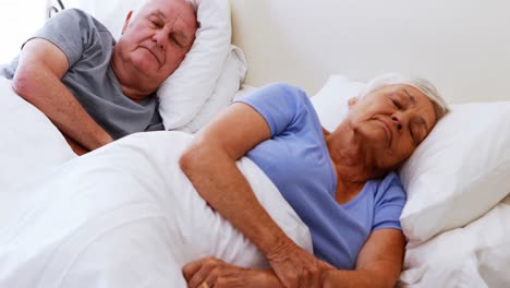 Senior-couple-sleeping-on-bed-in-bedroom