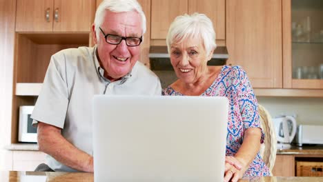 Smiling-couple-using-laptop-in-kitchen