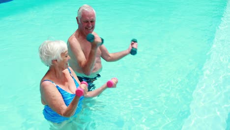 Älteres-Paar-Trainiert-Mit-Hanteln-Im-Pool