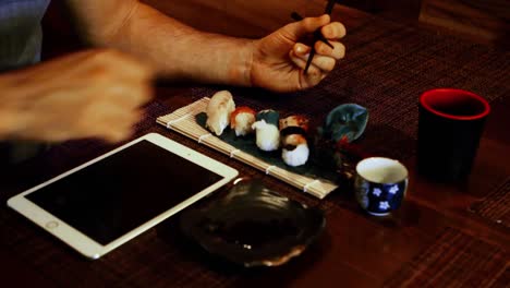 Mann-Benutzt-Digitales-Tablet,-Während-Er-Sushi-Im-Restaurant-Isst