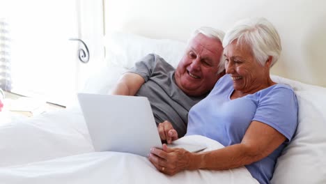 Glückliches-älteres-Paar,-Das-Laptop-Auf-Dem-Bett-Benutzt