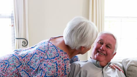 Senior-woman-kissing-senior-man-in-living-room