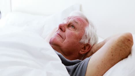Smiling-senior-man-lying-on-bed-in-bedroom
