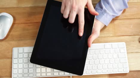Hand-of-businesswoman-using-digital-tablet-at-desk-with-keyboard-and-mouse-on-table