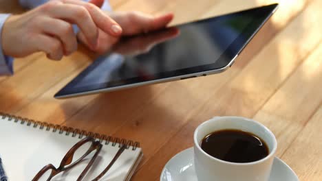 Geschäftsfrau-Nutzt-Digitales-Tablet-Am-Schreibtisch-Mit-Tasse-Kaffee,-Brille-Und-Notebook-Auf-Dem-Tisch