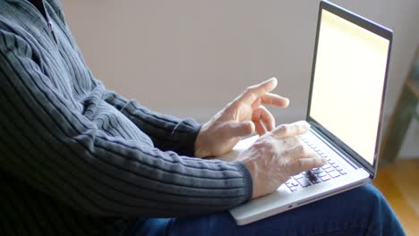Mid-section-of-man-using-laptop