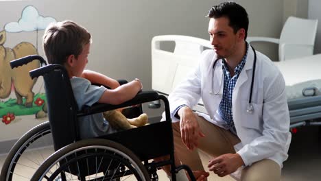 Male-doctor-interacting-with-child-patient-in-ward