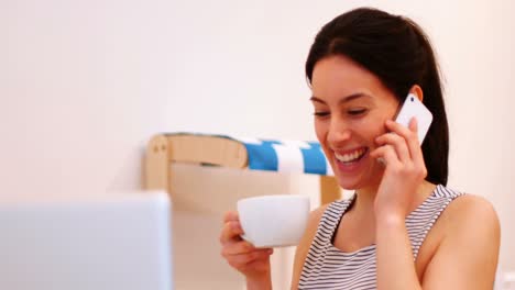 Woman-talking-on-mobile-phone-while-having-coffee