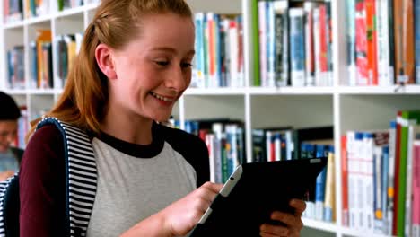 Lächelndes-Schulmädchen-Mit-Digitalem-Tablet-In-Der-Bibliothek