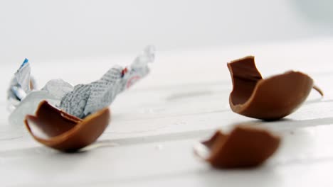 Zerbrochene-Schokoladen-Ostereier-Fallen-Auf-Eine-Holzoberfläche