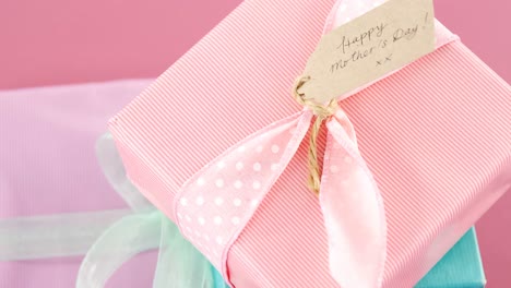 Gift-boxes-with-happy-mother-day-tag-against-pink-background