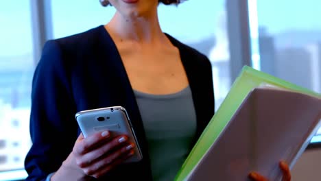 Lächelnde-Weibliche-Führungskraft,-Die-Im-Büro-Ihr-Mobiltelefon-Benutzt