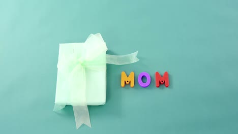 Gift-box-with-alphabets-displaying-mom-against-green-background