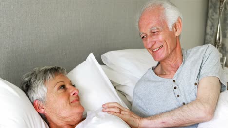 Senior-couple-interacting-with-each-other-on-bed-in-bedroom