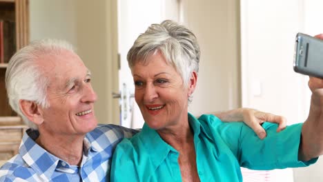 Senior-couple-taking-selfie-from-mobile-phone-in-the-living-room