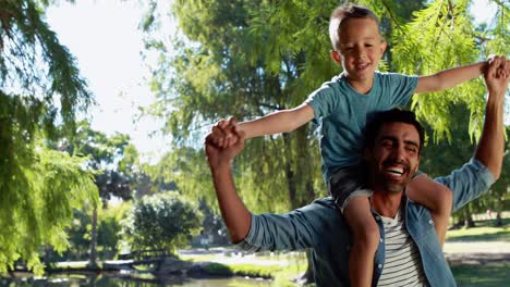 Father-carrying-son-on-his-shoulders-in-park
