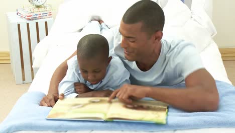Afroamerikanischer-Kleiner-Junge-Und-Sein-Vater-Lesen-Ein-Buch-Im-Schlafzimmer