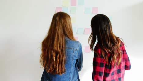 Female-executives-discussing-over-sticky-notes