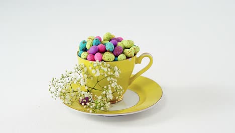 Tasse-Gefüllt-Mit-Bemalten-Schokoladen-Ostereiern-Und-Weißen-Blumen