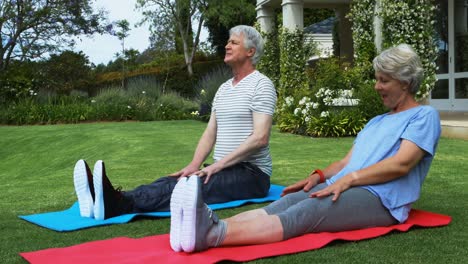Senior-couple-performing-stretching-exercise-on-exercise-mat