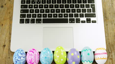 Huevos-De-Pascua-Pintados-Y-Computadora-Portátil-Sobre-Superficie-De-Madera