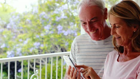 Glückliches-älteres-Paar,-Das-Mobiltelefon-Auf-Dem-Balkon-Benutzt
