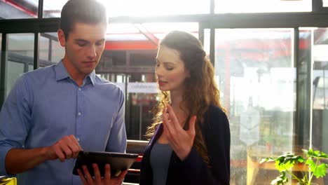 Male-and-female-executives-discussing-over-digital-tablet