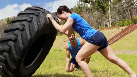 Male-trainer-giving-training-to-woman-during-obstacle-course