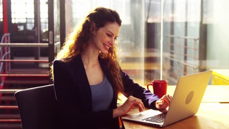 Weibliche-Führungskraft-Benutzt-Laptop-Beim-Kaffeetrinken