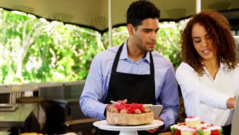 Male-and-female-waiter-discussing-over-clipboard-