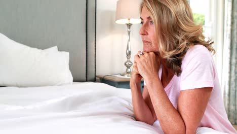 Thoughtful-woman-siting-on-bed-in-bedroom