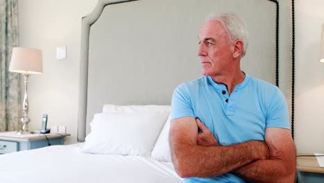 Thoughtful-man-siting-on-bed-in-bedroom