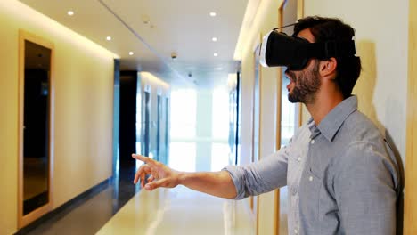 Male-executive-using-virtual-reality-headset-in-corridor