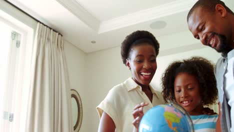 Parents-and-daughter-looking-at-globe-in-living-room